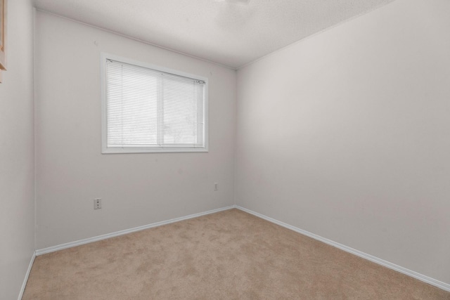 empty room featuring light colored carpet and baseboards