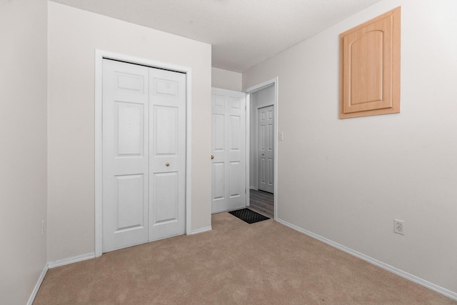 unfurnished bedroom featuring carpet, baseboards, and a closet