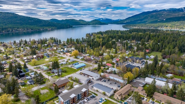 aerial view of property and surrounding area featuring a water and mountain view and a forest