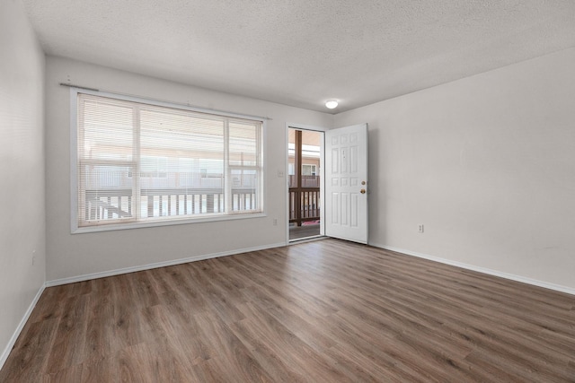 spare room with a textured ceiling, wood finished floors, and baseboards