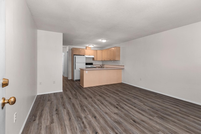kitchen with freestanding refrigerator, a peninsula, dark wood finished floors, open floor plan, and a textured ceiling