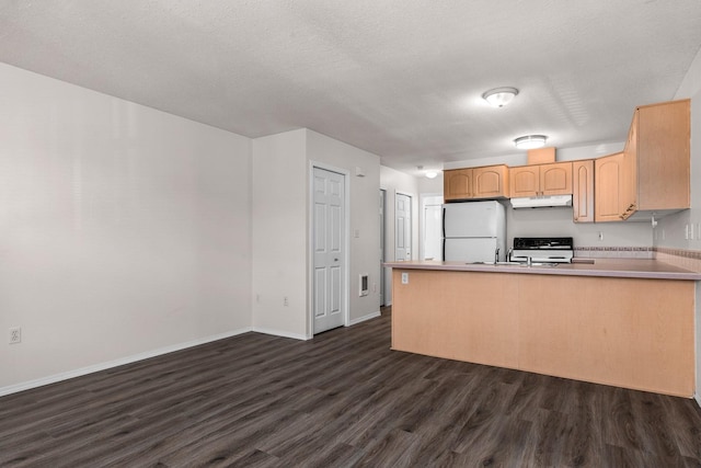 kitchen featuring freestanding refrigerator, under cabinet range hood, dark wood-type flooring, stove, and a peninsula