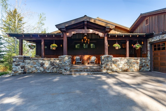 32220 Tamarack Dr, Bigfork, MT 59911 - view of front of house featuring covered porch, board and batten siding, an attached garage, and driveway