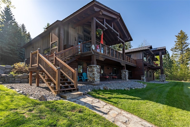 32220 Tamarack Dr, Bigfork, MT 59911 - view of front of house with a front yard, stairs, a wooden deck, a patio, and board and batten siding