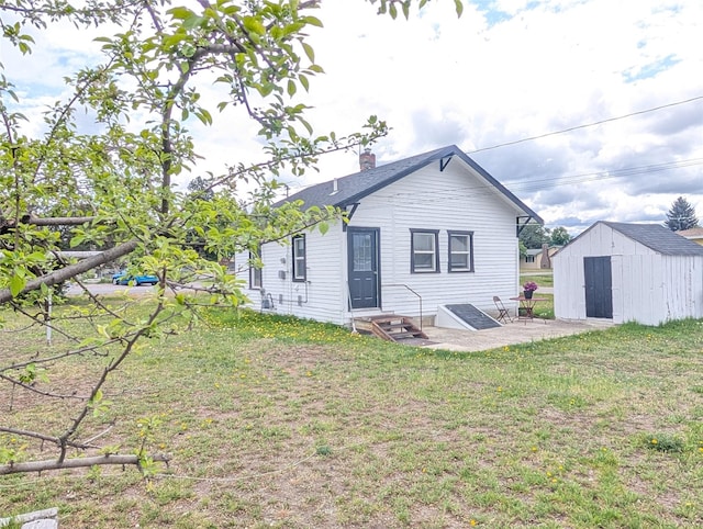 403 Mission St, Stevensville, MT 59870 - rear view of house with a lawn, a storage unit, a chimney, an outdoor structure, and entry steps