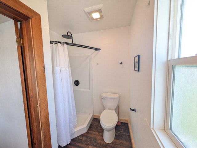 403 Mission St, Stevensville, MT 59870 - full bathroom with wood finished floors, curtained shower, toilet, and baseboards