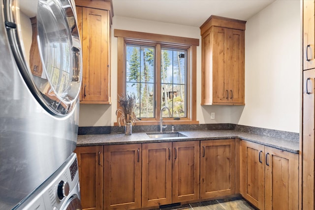 66 Elk Highlands Dr, Whitefish, MT 59937 - kitchen featuring stacked washing machine and dryer, dark countertops, a sink, and brown cabinets