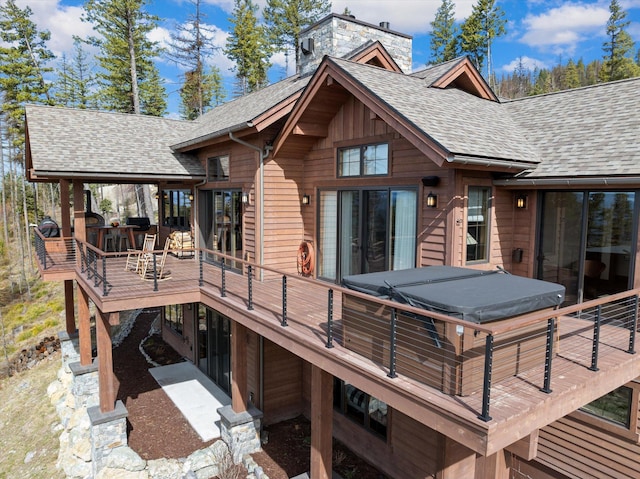 66 Elk Highlands Dr, Whitefish, MT 59937 - rear view of property with a hot tub, a shingled roof, a chimney, and a deck