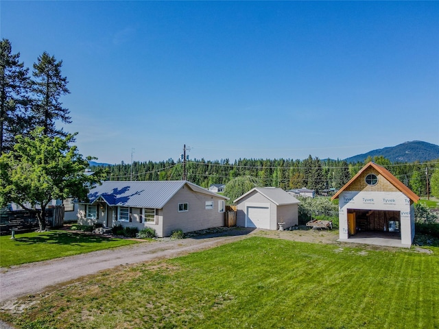 514 W 1st St, Libby, MT 59923 - view of front of home with a detached garage, a front yard, an outdoor structure, a mountain view, and metal roof