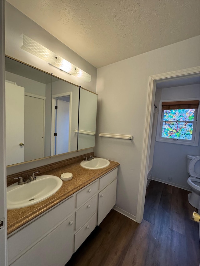 4900 Clearview Way, Missoula, MT 59803 - bathroom with wood finished floors, toilet, double vanity, baseboards, and a textured ceiling