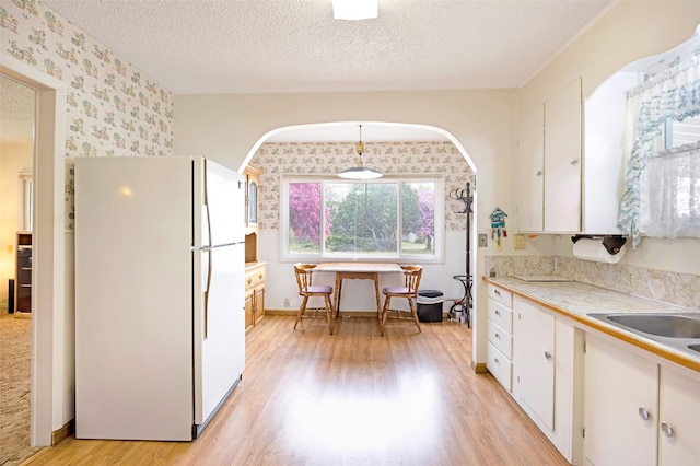 521 Buck St, Stevensville, MT 59870 - kitchen featuring freestanding refrigerator, wallpapered walls, light wood-type flooring, white cabinetry, and light countertops