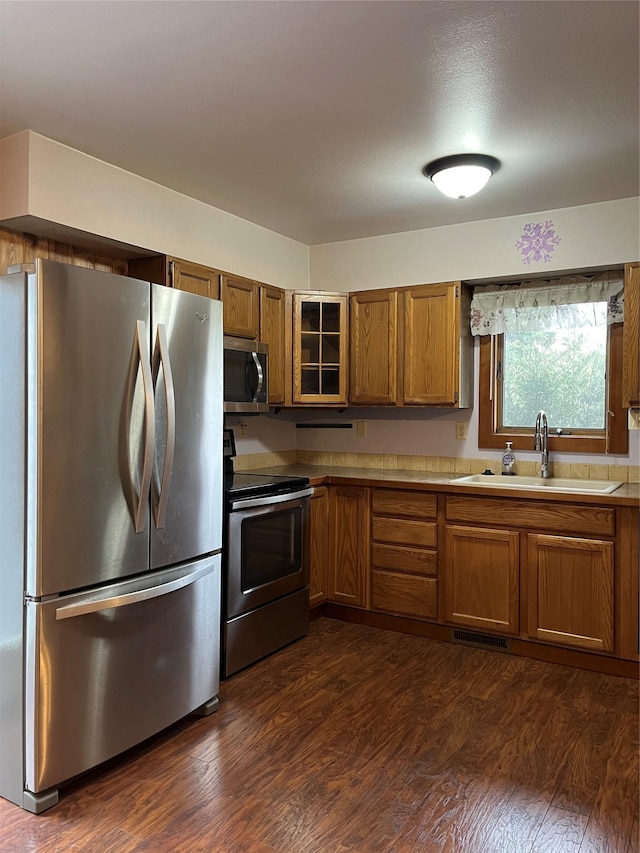 156 Clary Ave W, Geraldine, MT 59446 - kitchen featuring appliances with stainless steel finishes, brown cabinetry, dark wood-type flooring, and a sink