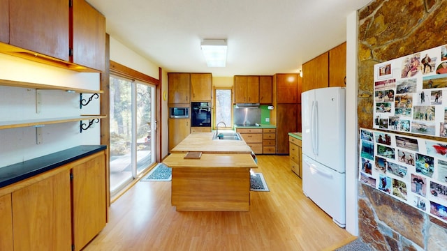 1487 Lion Mountain Dr, Whitefish, MT 59937 - kitchen featuring black appliances, a sink, light wood-style flooring, a kitchen island with sink, and brown cabinets