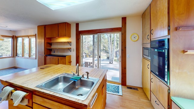 1487 Lion Mountain Dr, Whitefish, MT 59937 - kitchen featuring a sink, black oven, light wood-style flooring, stainless steel microwave, and brown cabinets