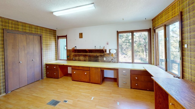 1487 Lion Mountain Dr, Whitefish, MT 59937 - unfurnished office featuring wallpapered walls, light wood finished floors, built in study area, and a textured ceiling