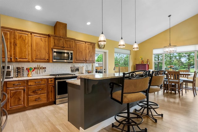 500 Bass Ln, Corvallis, MT 59828 - kitchen with stainless steel appliances, brown cabinets, a kitchen bar, backsplash, and light stone counters