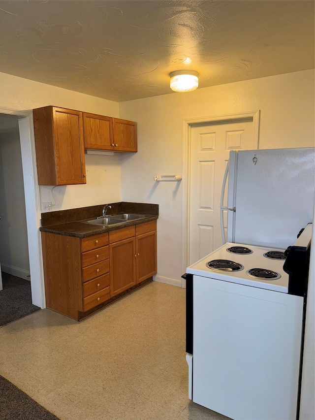 3946 E Ridge Rd, Butte, MT 59701 - kitchen with white appliances, brown cabinets, baseboards, a sink, and dark countertops