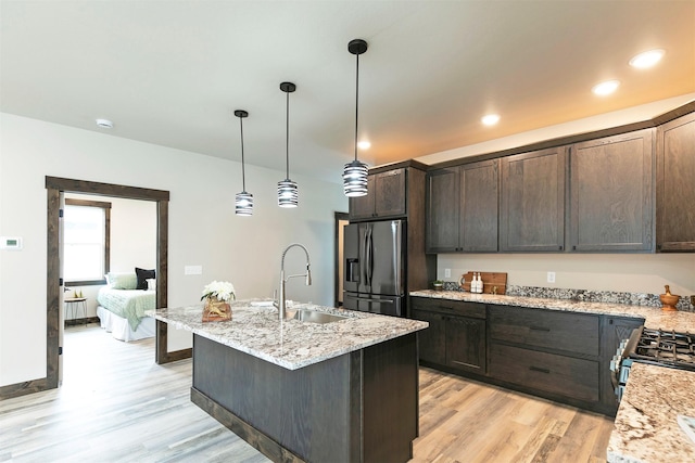5576 Cattle Dr, Missoula, MT 59808 - kitchen featuring stainless steel refrigerator with ice dispenser, a sink, light wood-style floors, dark brown cabinets, and light stone countertops
