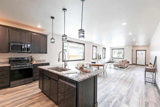 5576 Cattle Dr, Missoula, MT 59808 - kitchen featuring appliances with stainless steel finishes, a sink, dark brown cabinets, open floor plan, and light wood-type flooring