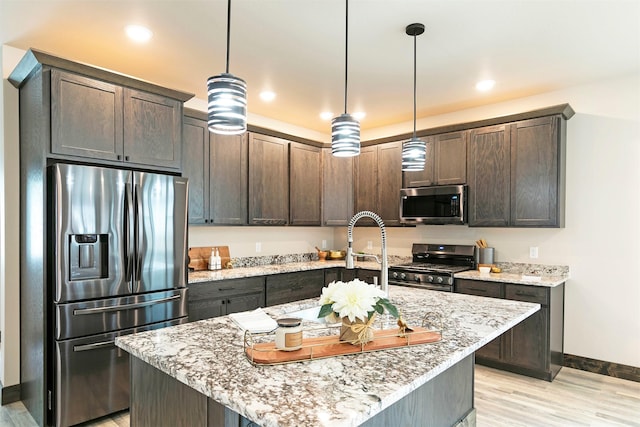 5576 Cattle Dr, Missoula, MT 59808 - kitchen with appliances with stainless steel finishes, baseboards, light wood-style floors, dark brown cabinets, and light stone countertops