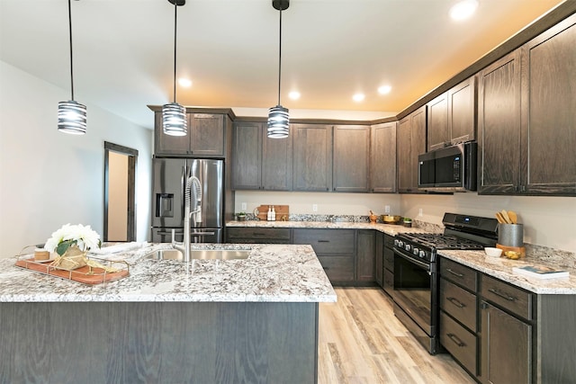 5576 Cattle Dr, Missoula, MT 59808 - kitchen with appliances with stainless steel finishes, a sink, dark brown cabinets, light wood-style flooring, and light stone countertops