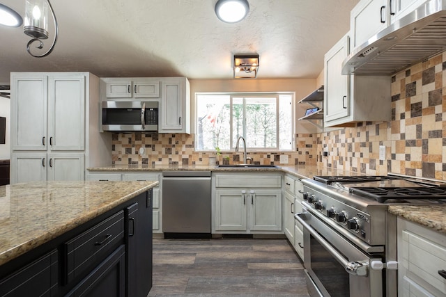 6400 Boondock Ln, Clinton, MT 59825 - kitchen featuring appliances with stainless steel finishes, under cabinet range hood, dark wood-style floors, backsplash, and light stone countertops