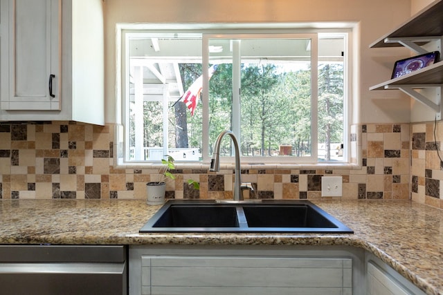 kitchen featuring a sink, dishwasher, white cabinetry, decorative backsplash, and plenty of natural light
