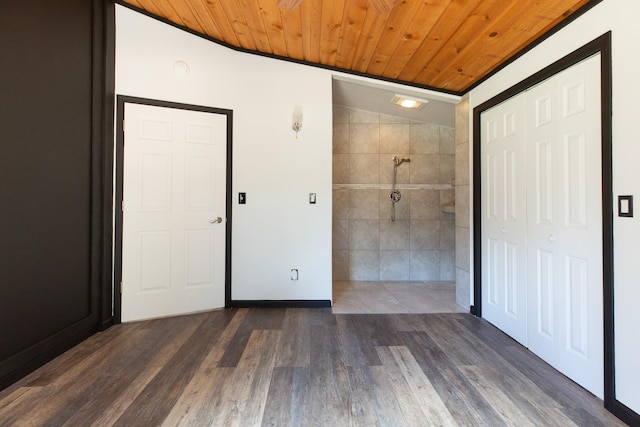 unfurnished bedroom featuring wood finished floors, wood ceiling, ensuite bathroom, tile walls, and a closet