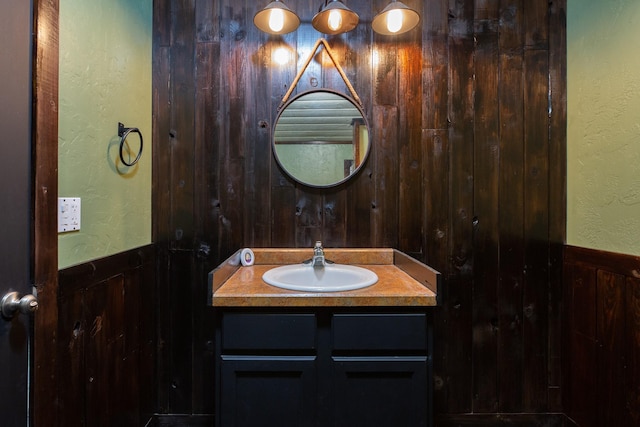 bathroom featuring a wainscoted wall, wood walls, and vanity