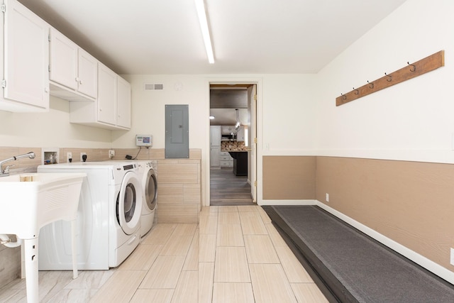 washroom with cabinet space, washer and clothes dryer, and electric panel