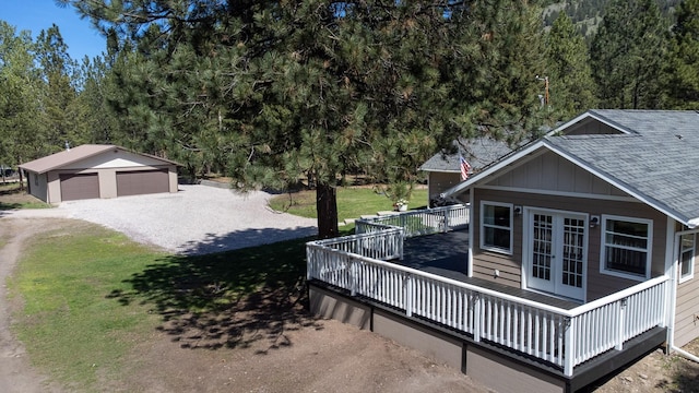6400 Boondock Ln, Clinton, MT 59825 - view of home's exterior featuring french doors, an outdoor structure, roof with shingles, a wooden deck, and a detached garage