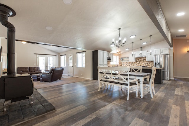 dining space featuring baseboards, dark wood-style floors, a chandelier, and a wood stove