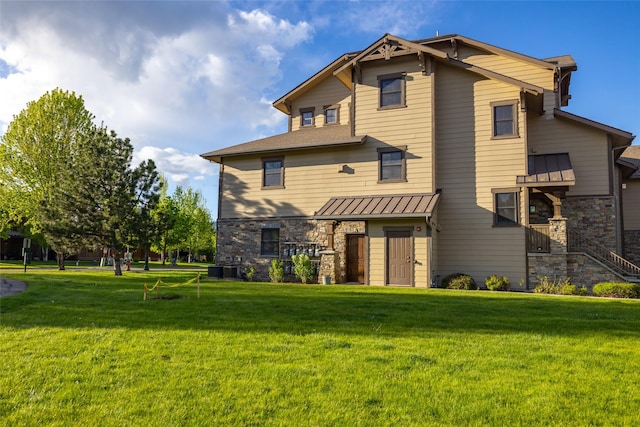 6002 St Moritz Dr Unit A, Whitefish, MT 59937 - rear view of house with a lawn, a standing seam roof, stone siding, and metal roof