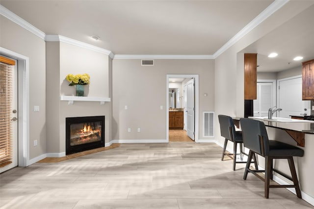 6002 St Moritz Dr Unit A, Whitefish, MT 59937 - kitchen with ornamental molding, a kitchen breakfast bar, baseboards, a glass covered fireplace, and recessed lighting
