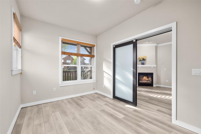 6002 St Moritz Dr Unit A, Whitefish, MT 59937 - spare room with light wood-style flooring, baseboards, and a glass covered fireplace