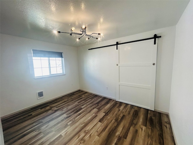 4 Weber Ave, Polson, MT 59860 - unfurnished bedroom featuring a barn door, dark wood-type flooring, and a chandelier