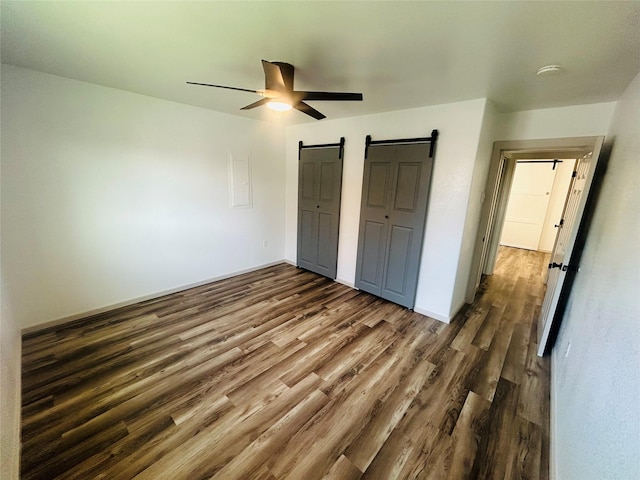 4 Weber Ave, Polson, MT 59860 - unfurnished bedroom featuring a barn door, wood finished floors, and a ceiling fan