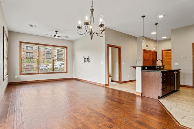 kitchen with dark countertops, a ceiling fan, open floor plan, light wood finished floors, and baseboards