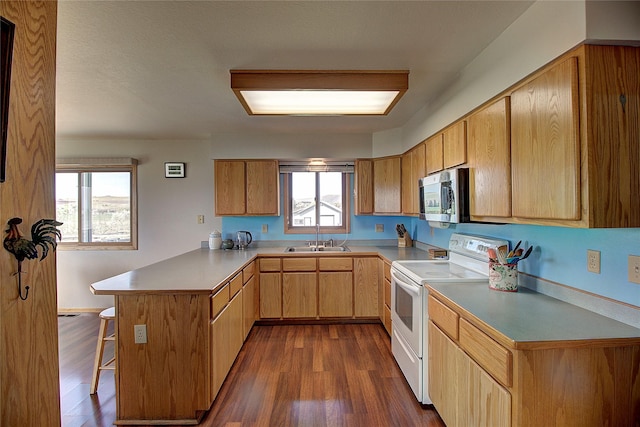 kitchen featuring white electric stove, stainless steel microwave, a peninsula, a sink, and a breakfast bar