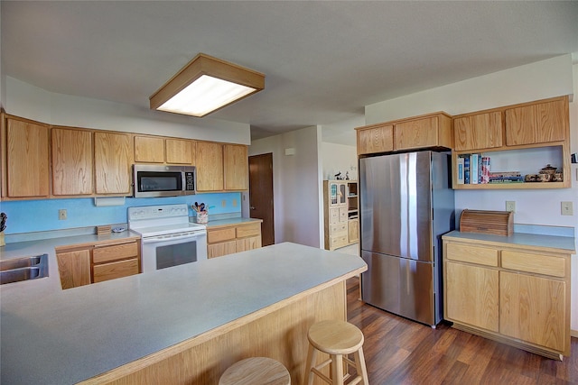 kitchen featuring appliances with stainless steel finishes, dark wood-type flooring, a peninsula, a sink, and light brown cabinetry