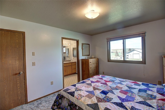 bedroom featuring a sink, baseboards, connected bathroom, a textured ceiling, and light carpet