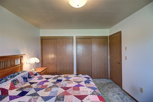 carpeted bedroom featuring multiple closets and a textured ceiling