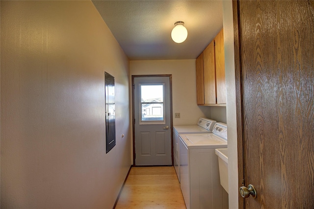 clothes washing area with cabinet space, washing machine and clothes dryer, and light wood-style floors