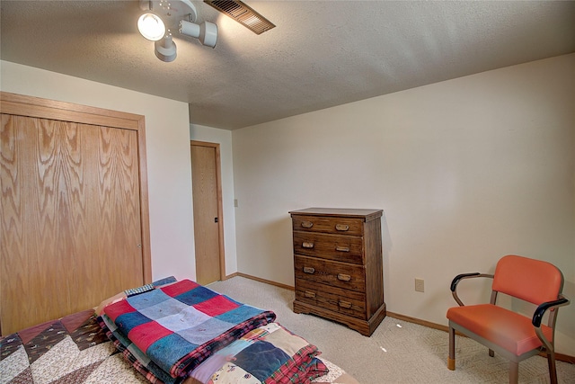 bedroom featuring light carpet, baseboards, and a textured ceiling