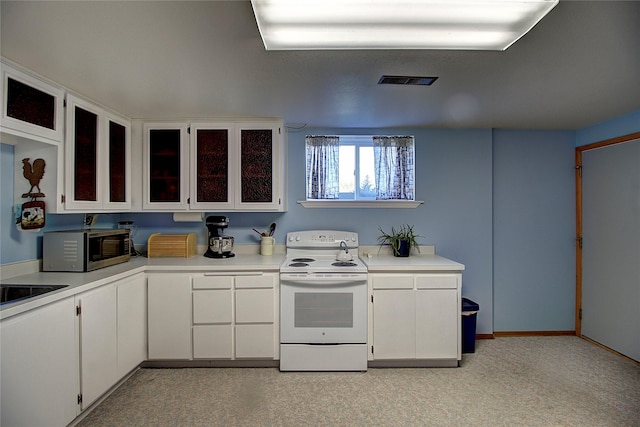 kitchen with white range with electric cooktop, stainless steel microwave, light countertops, white cabinetry, and glass insert cabinets