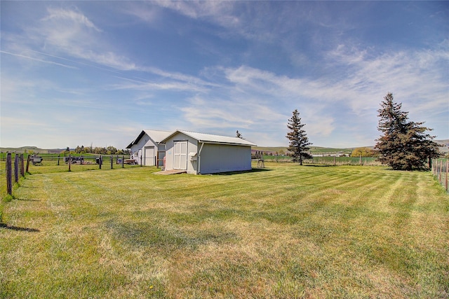 view of yard featuring a view of countryside, an outdoor structure, and a shed