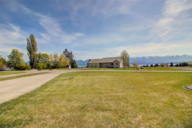 view of front of property with a front yard, concrete driveway, and a mountain view