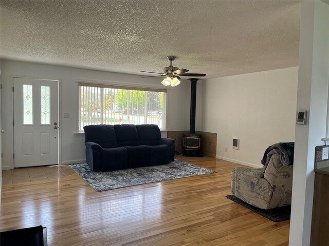 403 S Cherry St, Townsend, MT 59644 - living area with a textured ceiling, wood finished floors, a wood stove, ceiling fan, and baseboards
