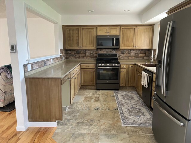 403 S Cherry St, Townsend, MT 59644 - kitchen with appliances with stainless steel finishes, decorative backsplash, a sink, brown cabinetry, and light countertops