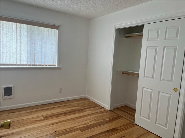 403 S Cherry St, Townsend, MT 59644 - unfurnished bedroom featuring wood finished floors, a closet, a textured ceiling, baseboards, and heating unit